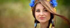 Zdjęcie przedstawia lekko uśmiechniętą kobietę z niebiesko-żółtym wiankiem na głowie.