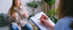 Fotografia przedstawia dwie kobiety: jedna przeprowadza z drugą wywiad psychologiczny.