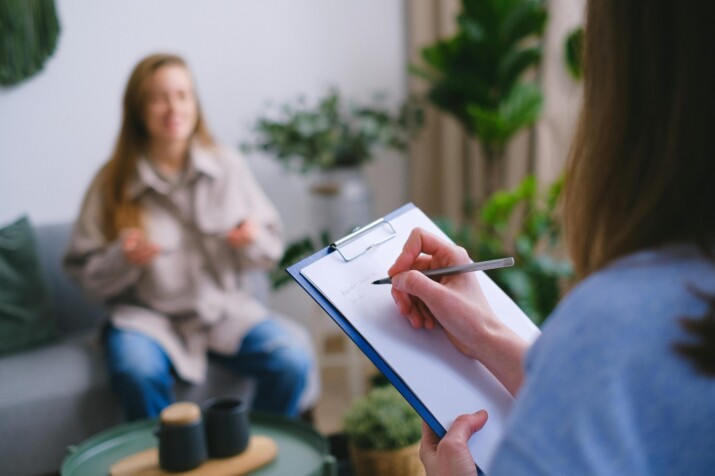 Fotografia przedstawia dwie kobiety: jedna przeprowadza z drugą wywiad psychologiczny.